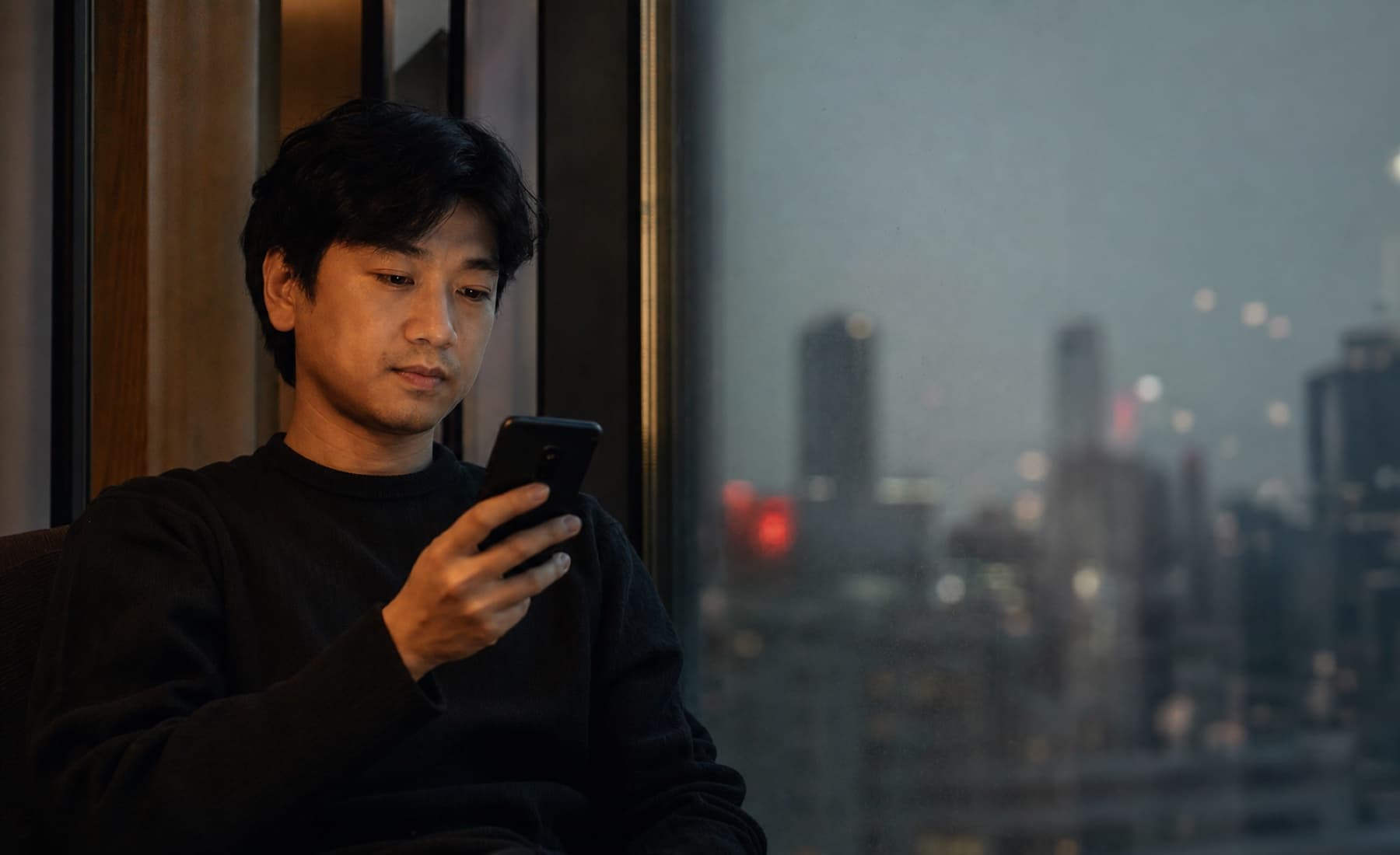 A KMP customer using their phone beside a city window